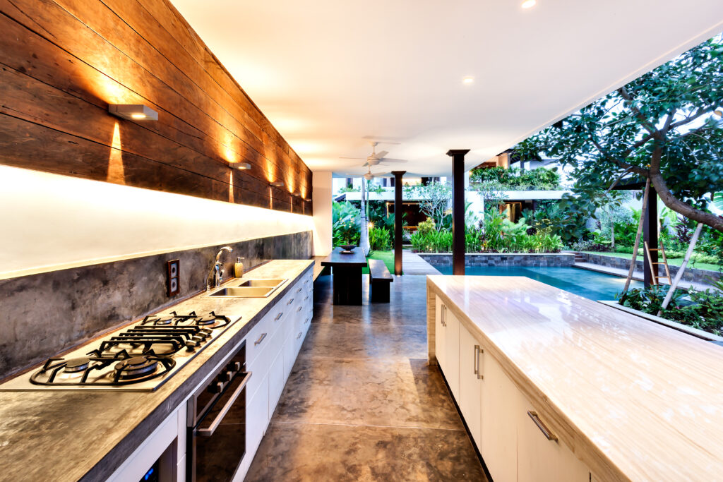 Outdoor kitchen with a stove an countertop next to garden including a pool in luxury hotel or house. outdoor countertop material